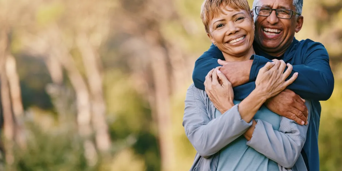 nature, love and portrait of a senior couple hugging in a garden while on romantic outdoor date happy, smile and elderly people in retirement embracing in park while on a walk for fresh air together