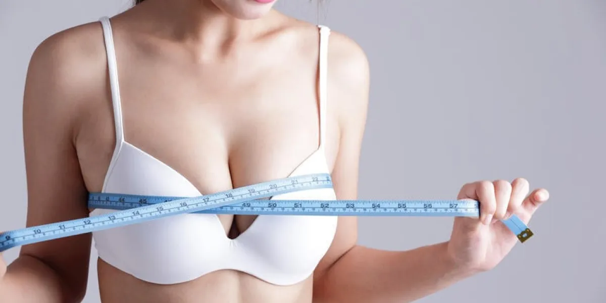 jeune femme, vérification, elle, poitrine, mesure, isolé, sur, arrière-plan gris, beauté asiatique