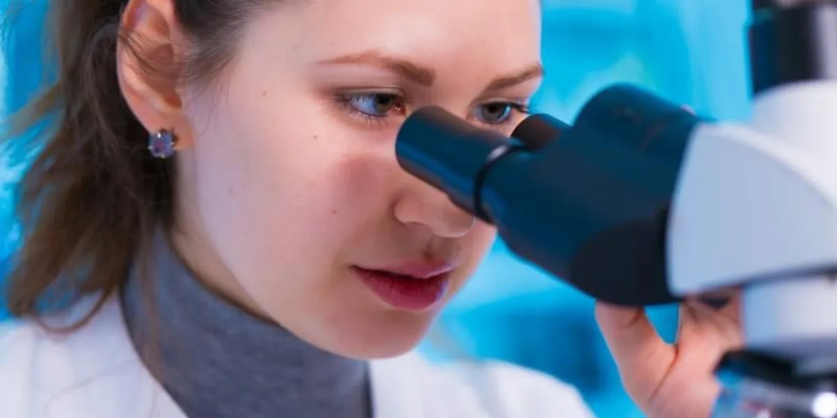 femme scientifique regardant à travers un microscope en laboratoire