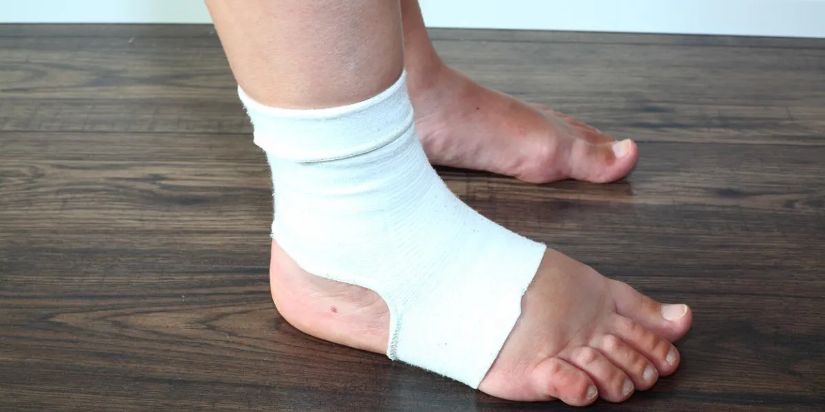 an image of woman's swollen feet standing on the floor, one foot is swollen and woman is wearing a compression sock (tensor bandage) to decrease swelling woman is 41 weeks pregnant (overdue) pregnancy problems and complications