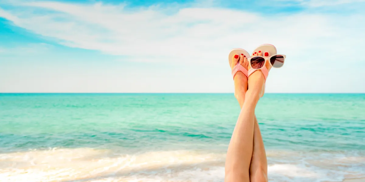 upside woman feet and red pedicure wear pink sandals, sunglasses at seaside funny and happy fashion young woman relax on vacation girl on beach creative for tour agent weekend travel summer vibes
