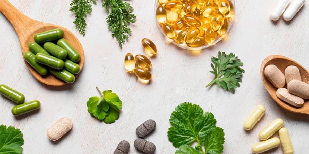 natural vitamins, plant based supplements and green leaves flat lay on white wooden background various organic capsules and pills, banner