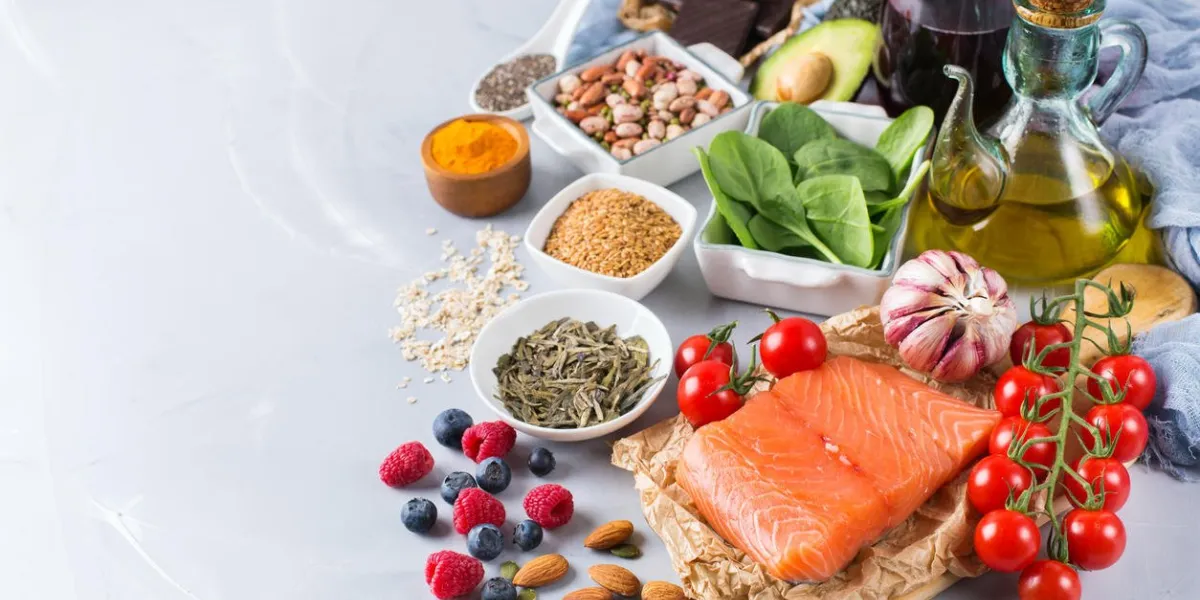 balanced diet food concept assortment of healthy food low cholesterol, spinach avocado red wine green tea salmon tomato berries flax chia seeds turmeric garlic nuts olive oil copy space background
