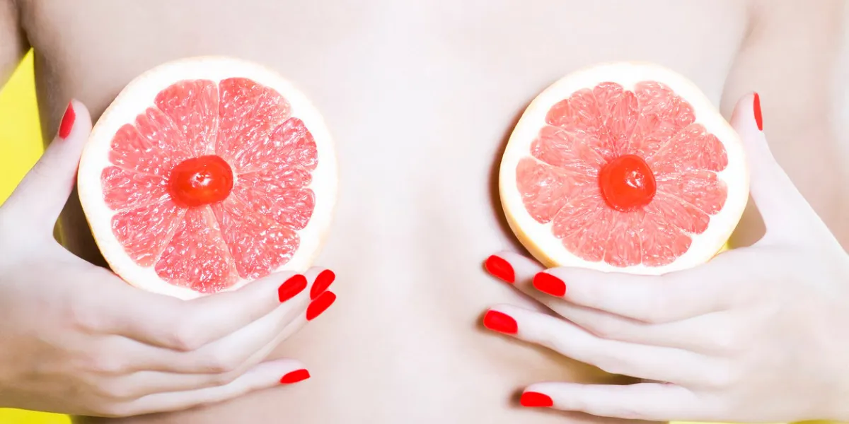 woman holding grapefruit in front of her breast