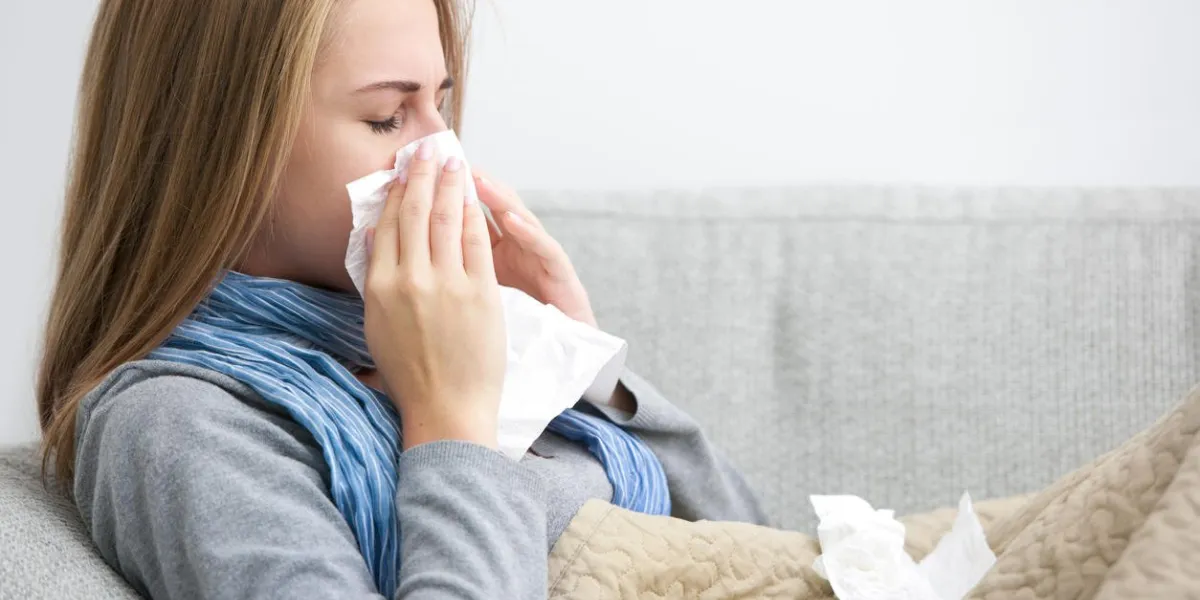 close up of a young woman sneezing into a tissue
