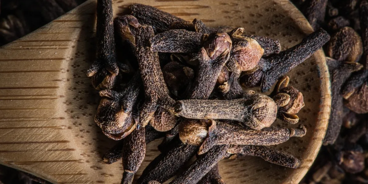 cuillère en bois avec des clous de girofle dans un tas de clous de girofle