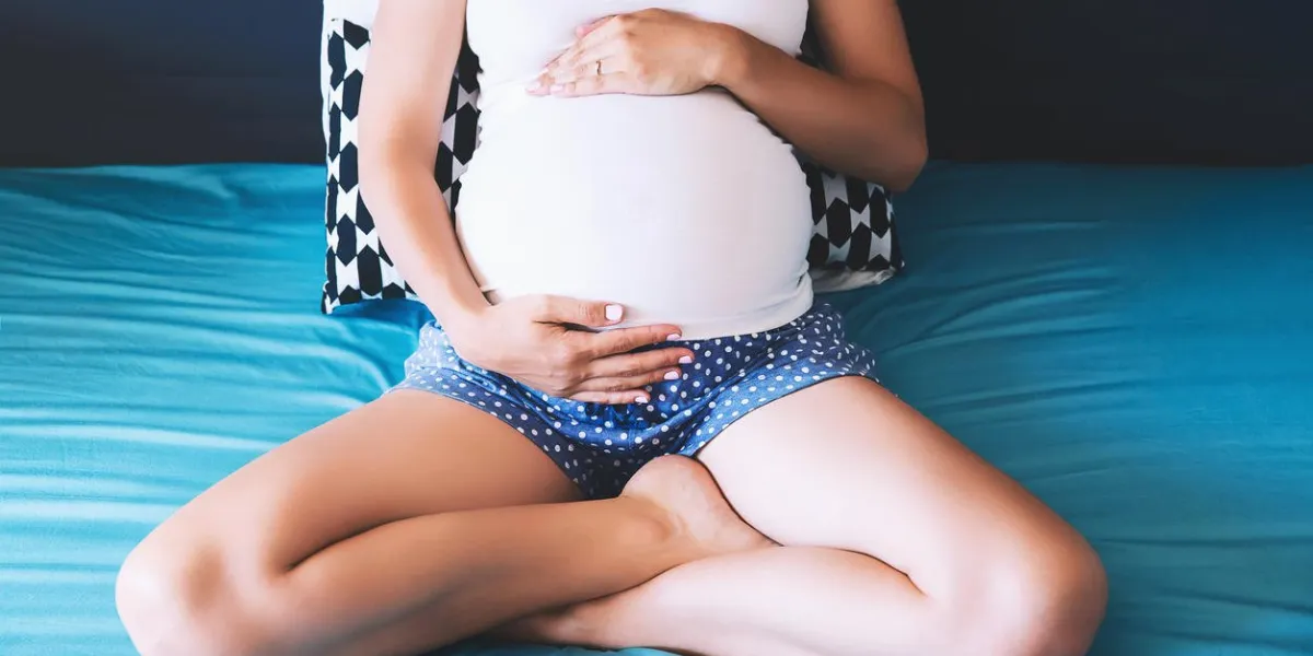 beautiful pregnant woman holds hands on belly in bedroom at home young mother waiting of a baby concept of pregnancy, maternity, health care, gynecology, medicine close-up, indoors