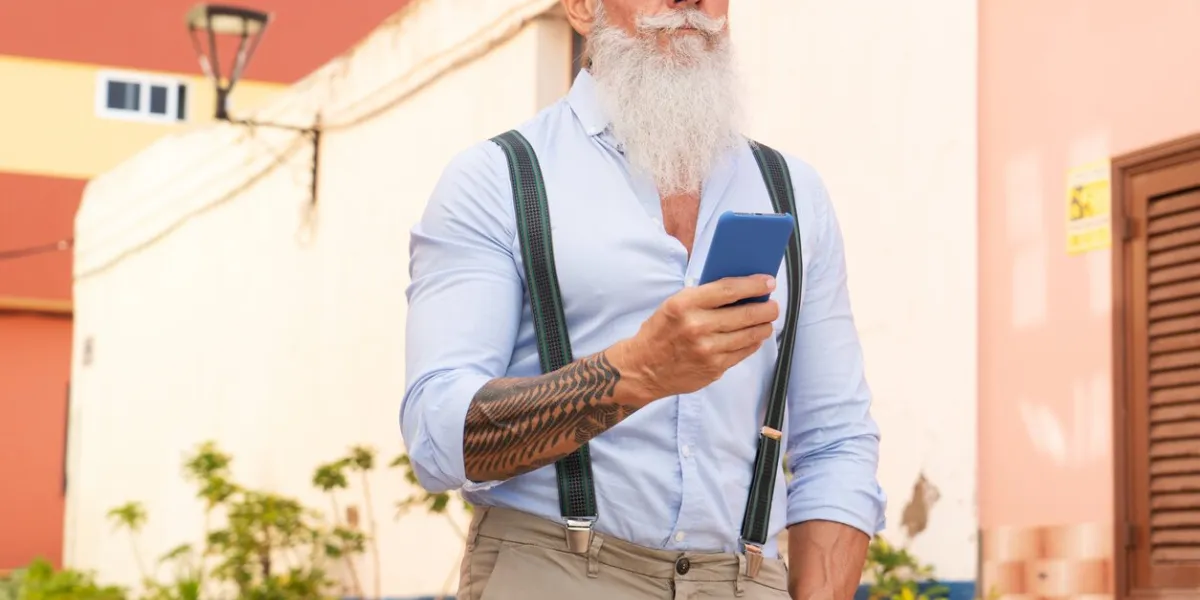 senior hipster man having fun with a phone on a europen city street, happiness, technology and elderly lifestyle people concept