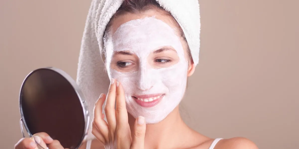 jeune fille appliquant un masque sur son visage et regardant dans le miroir