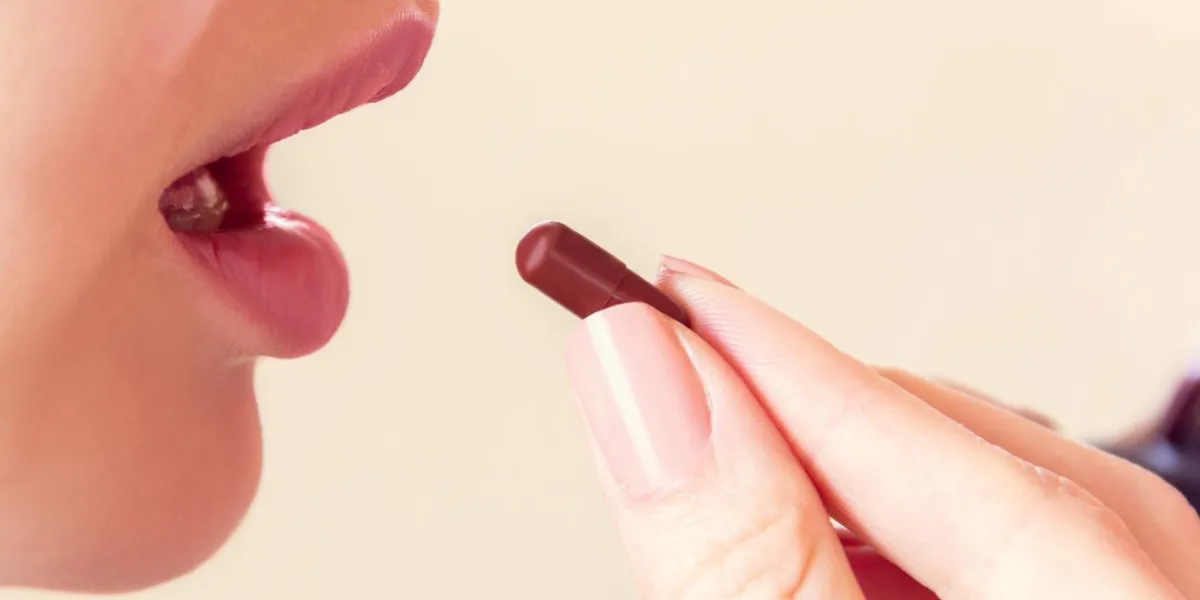 girl takes a pill with her mouth, close-up face and hand
