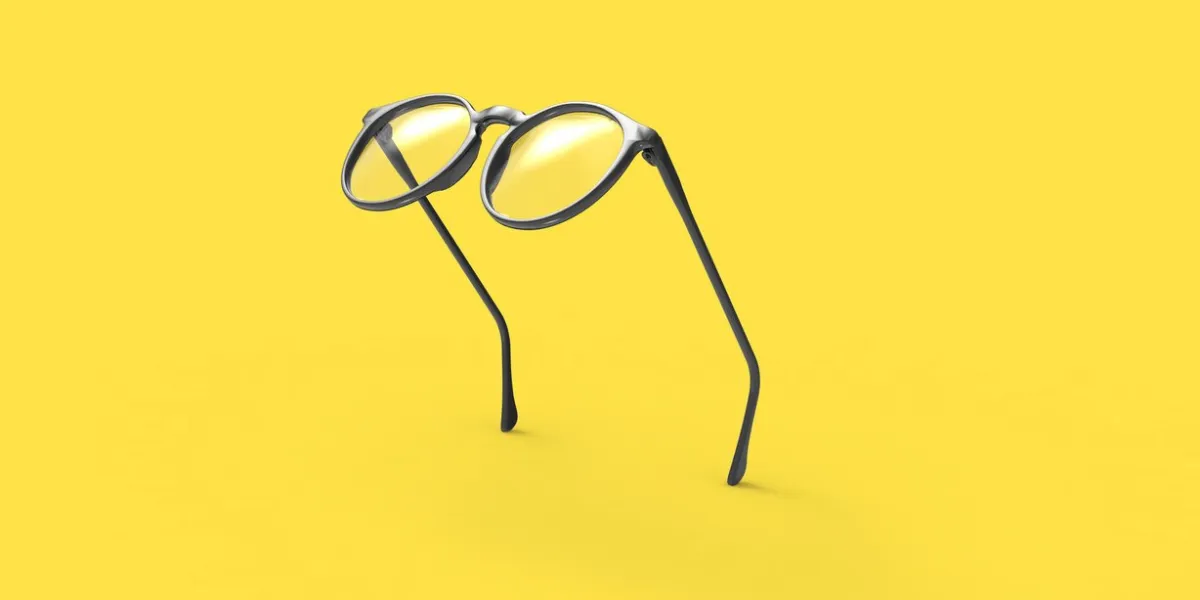 studio shot of flying black glasses on yellow background
