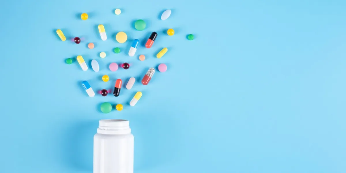 assorted pharmaceutical medicine pills, tablets and white bottle on blue background copy space for text