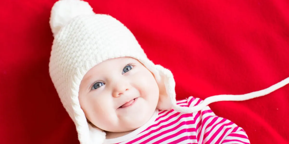 rire bébé heureux sur un fond rouge avec un grand chapeau blanc
