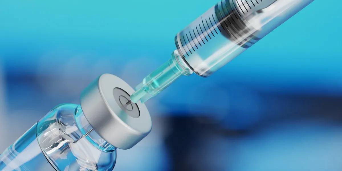medical disposable syringe for vaccine injection and glass vial on blue blur background