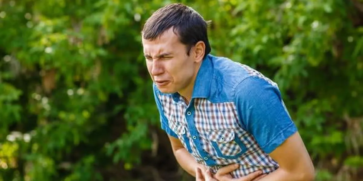 l'homme dans la rue des douleurs abdominales sur un fond vert laisse son