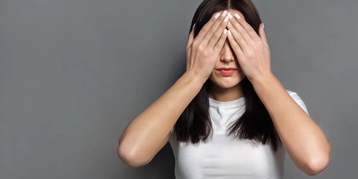 see no evil concept portrait of young scared woman covering eyes with hands while standing against gray studio background confused girl close eyes with palms ignoring something
