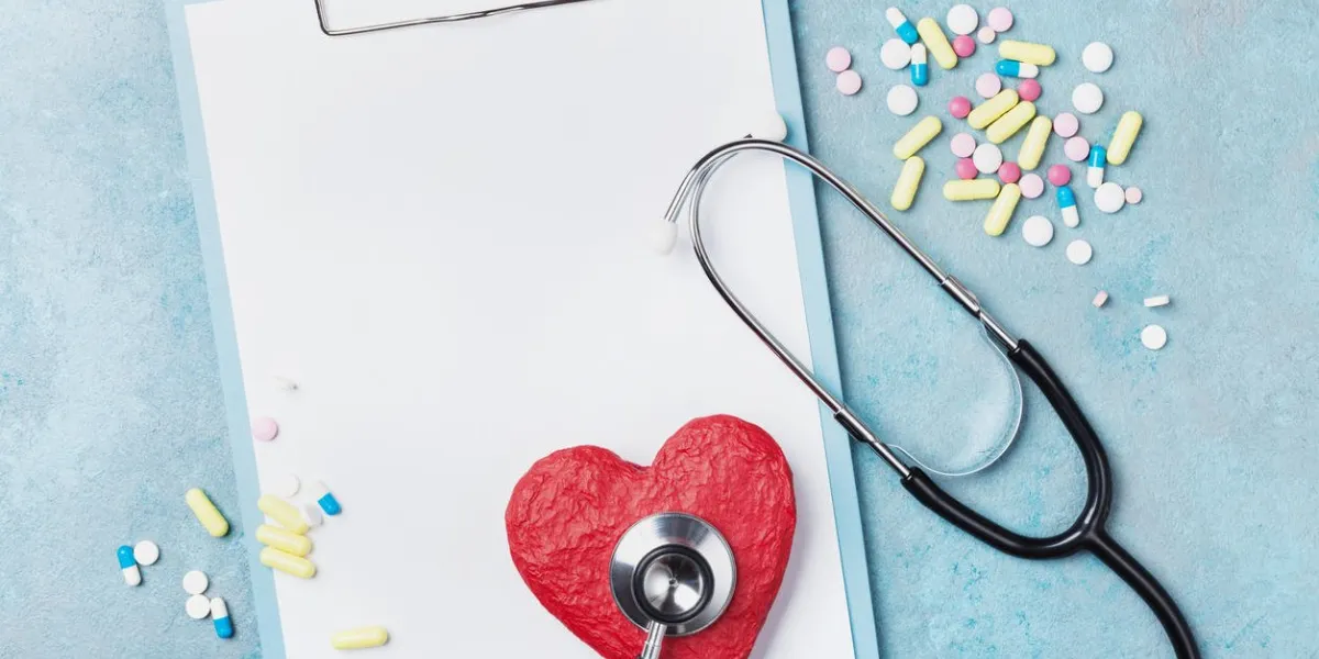 medicine clipboard, stethoscope, drug pills, and red shape of heart on blue background top view healthy and cardiology concept copy space for text