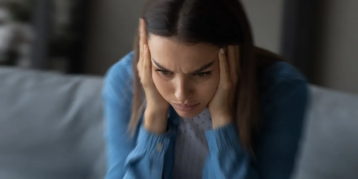 close up unhappy woman suffering from strong headache and dizziness, depressed young female blurry motion background, sitting on couch alone, touching temples, feeling pain, unwell and unhealthy
