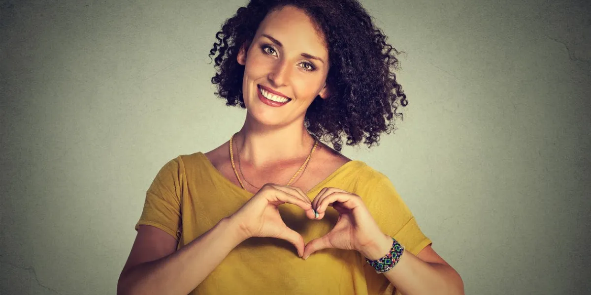 closeup, portrait, gai, heureux, jeune, femme, faire, coeur, signe, à, mains, isolé, gris, mur, fond, positif, émotion humaine, expression, sentiment, vie, perception, attitude, corps, langage