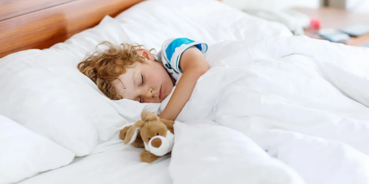 garçon adorable gamin dormir et rêver dans son lit blanc avec jouet