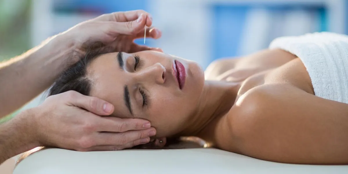 physiothérapeute masculin donnant un massage de la tête à une patiente en clinique