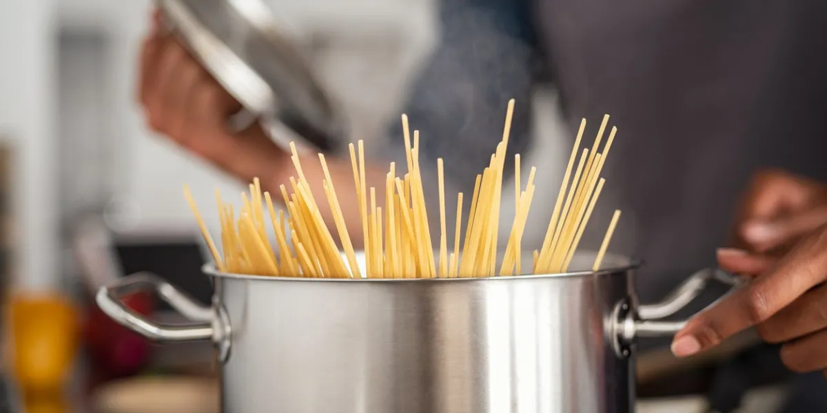 closeup of spaghetti in pot on stove woman holding pot with spaghetti in hot boiling water spaghetti ready to be cooked at home