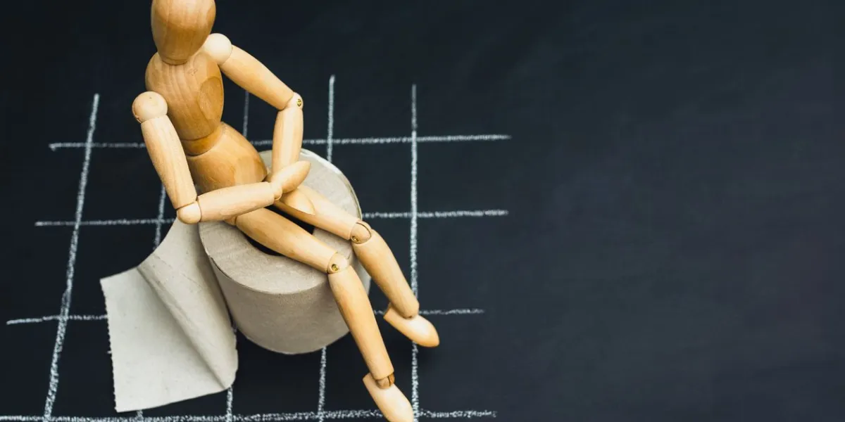 wooden figure sit on a roll of toilet paper concept of the problem with digestion