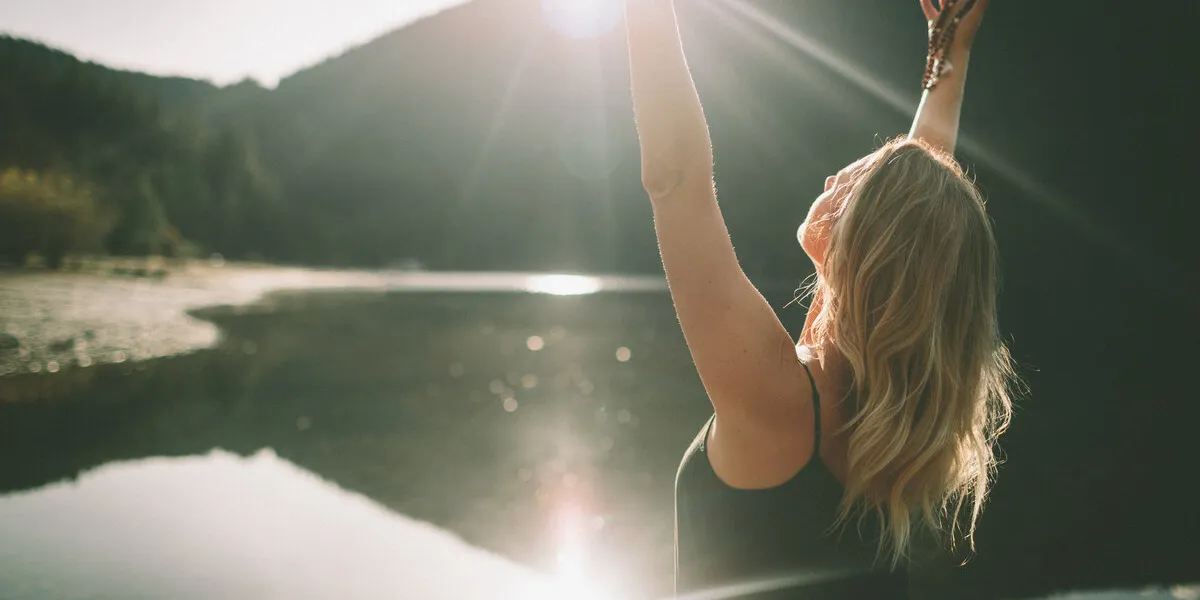 a woman meditating and expressing gratitude on a beach at sunrise