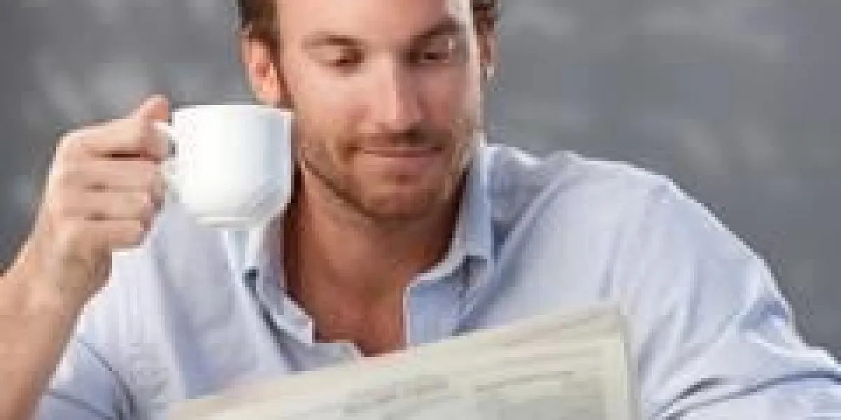 portrait du matin de beau mec lire le journal et tenant la tasse de café