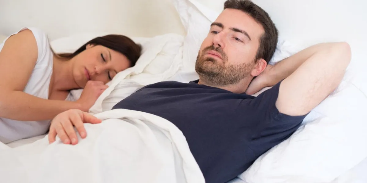sad and depressed man lying in the bed with his wife