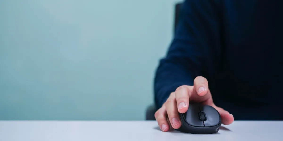 close up employee man hand using mouse cursor for scrolling web page or working on computer program at desktop in office concept