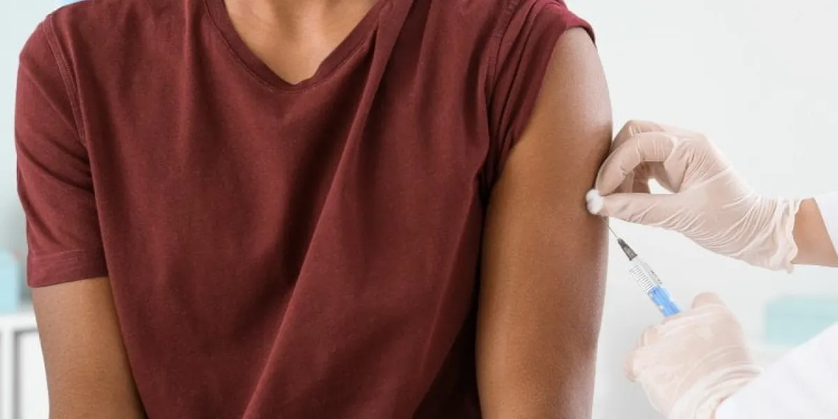 doctor vaccinating teenage boy in clinic, closeup