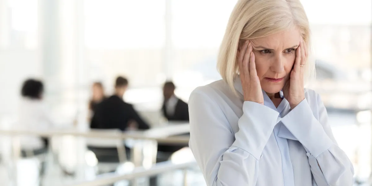 stressed fatigued mature businesswoman touching temples suffer from headache migraine at office meeting, tired exhausted old woman employee feels dizzy at work, climax and hormone imbalance concept