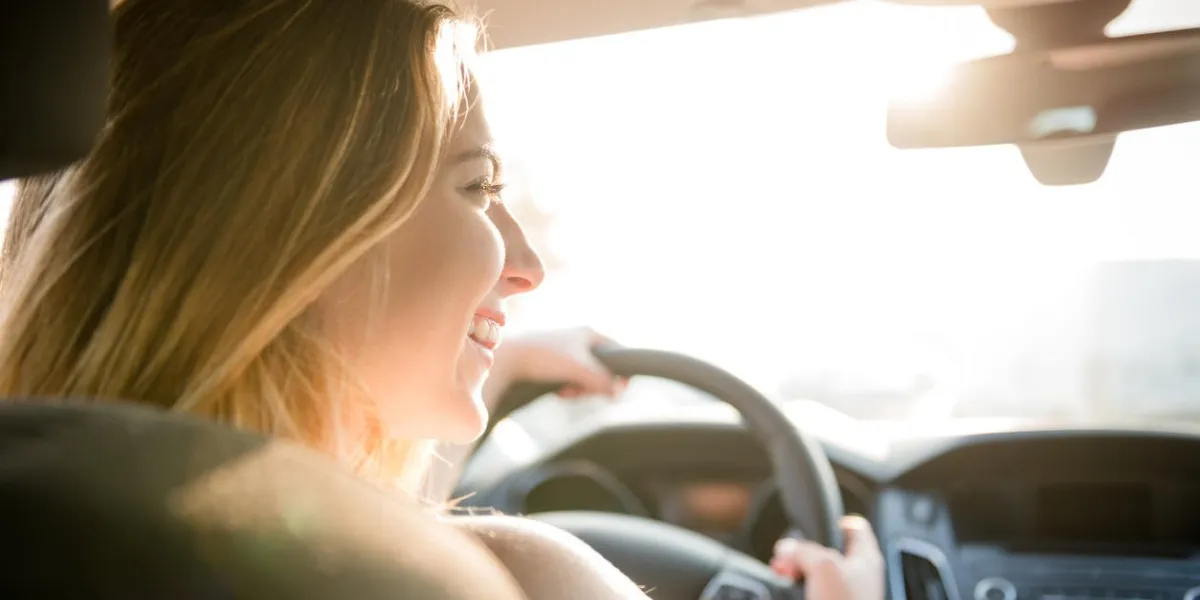adolescente au volant de voiture - vue arrière, le soleil est visible à travers la fenêtre avant