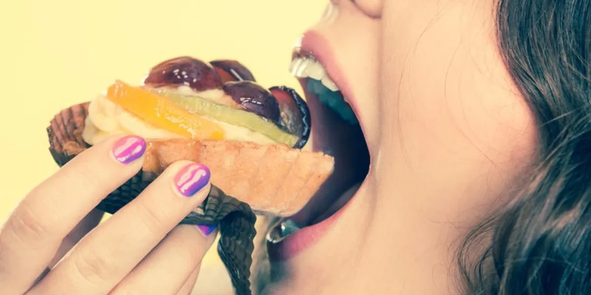 douceur et bonheur concept closeup mignonne femme cheveux frisés, manger, fruit, gâteau, cupcake, figure, profil, fond jaune