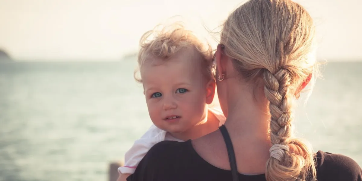enfant avec un regard sincère serrant sa mère assise sur ses mains et regardant la caméra mère tenant son bébé et regardant au loin vers l'horizon, enfant regardant la caméra