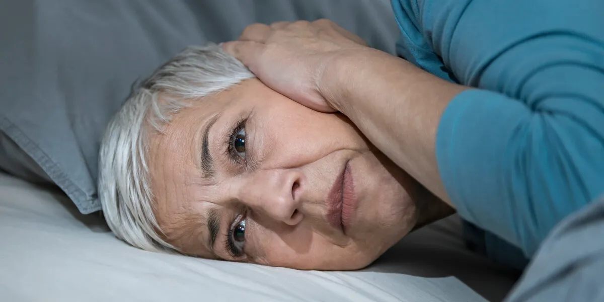 mature woman suffering from hyperacusis or misophonia, lying in bed awake at night