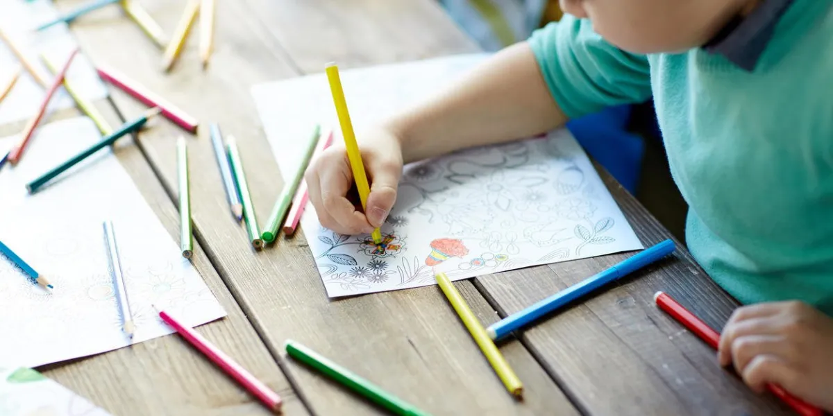 petit garçon assis et dessiner avec des crayons de couleur