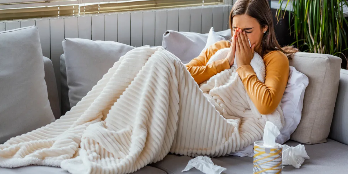 cold and flu portrait of ill woman caught cold, feeling sick and sneezing in paper wipe closeup of beautiful unhealthy girl covered in blanket wiping nose healthcare concept high resolution