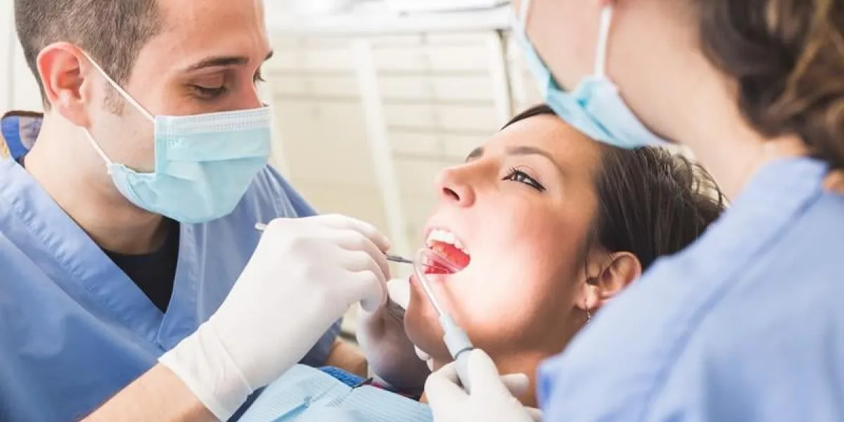 dentiste et assistante dentaire examinant les dents du patient dentiste est un homme, un assistant et un patient sont des femmes patientes qui sourient et n'ont pas peur du dentiste