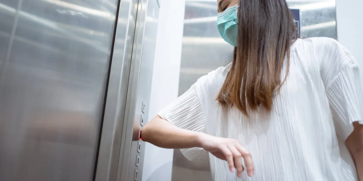 asian women use elbows to press elevator button to avoid using hands