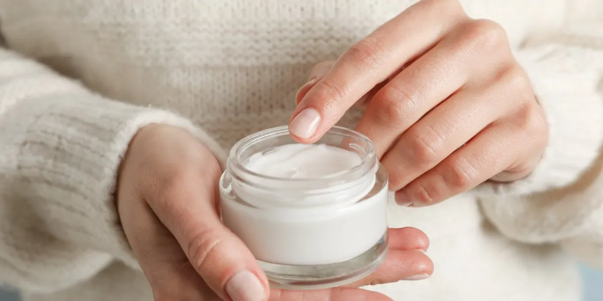 woman holding jar of moisturizing cream, closeup winter cosmetic space for text