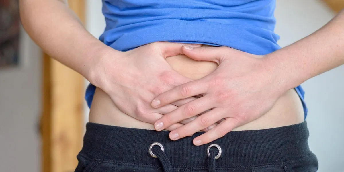 corps de la jeune femme avec les mains sur l'estomac nu pendant la période