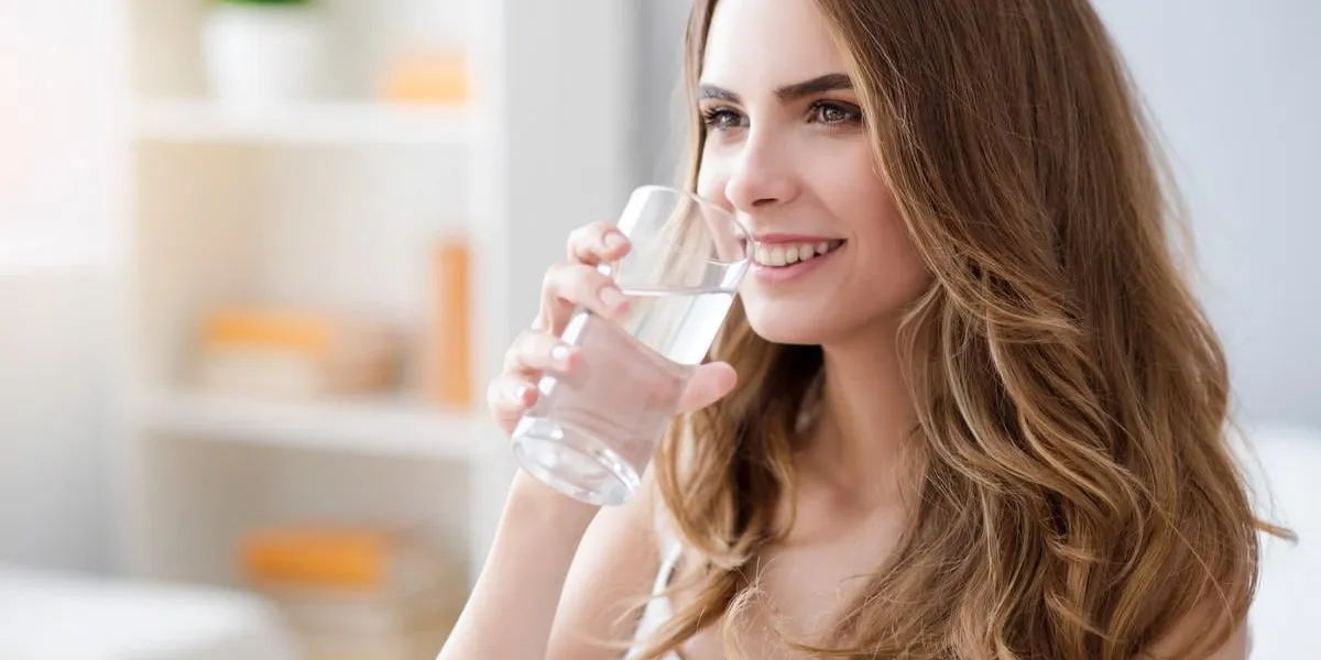 ma dose de positivité joyeuse ravie belle femme tenant le verre et l'eau potable en souriant
