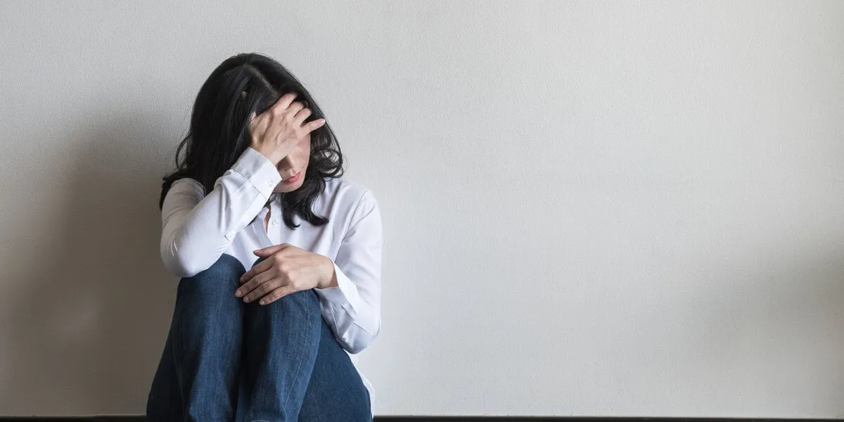 anxiety disorder menopause woman, stressful depressed, panic attack person with mental health illness, headache and migraine sitting with back against wall on the floor in domestic home