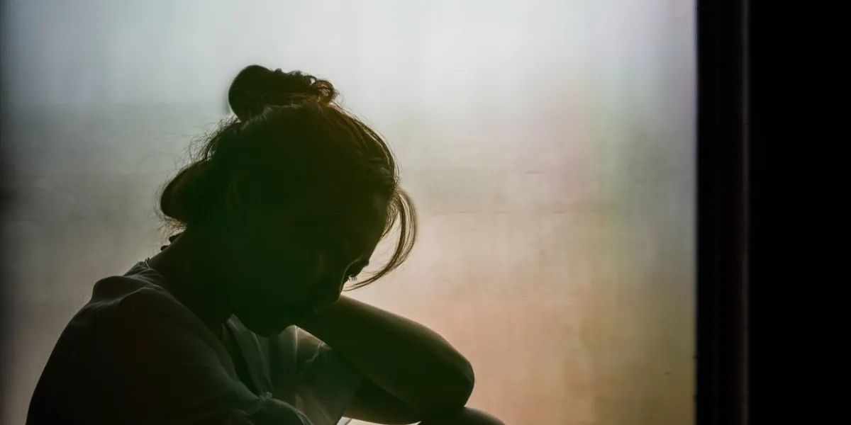 vintage filtered on silhouette of depressed girl sitting on the window