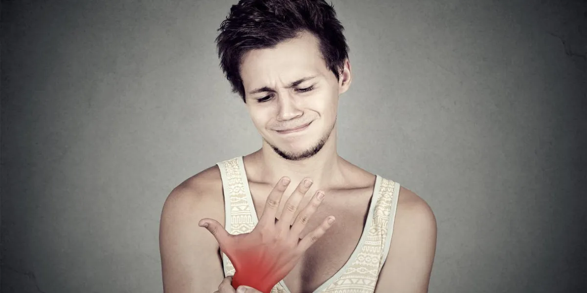 jeune homme, tenue, elle, douloureux, poignet, isolé, sur, gris, mur, fond, entorse, douleur, endroit, indiqué, par, tache rouge