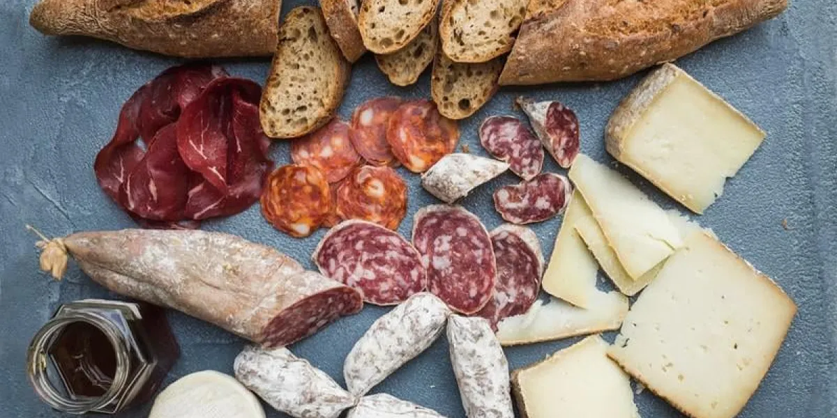 sélection de hors-d'oeuvre de fromage et de viande ou ensemble de collation de vin variété de fromage italien, salami, bresaola, baguette et miel sur fond de béton gris-bleu, vue de dessus