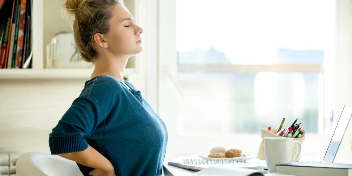 portrait d'une jolie femme dans une chaise à la table avec tasse et ordinateur portable, livre, crayons, bloc-notes sur elle photo concept