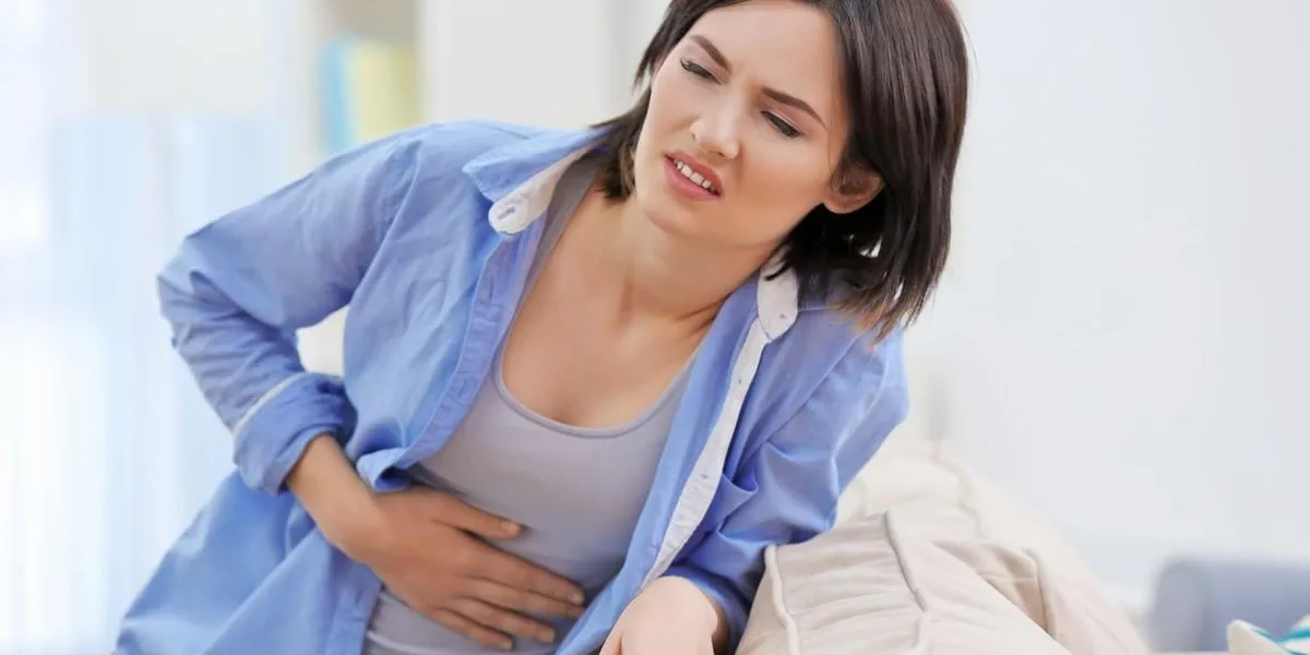 beautiful young woman suffering from stomach ache at home